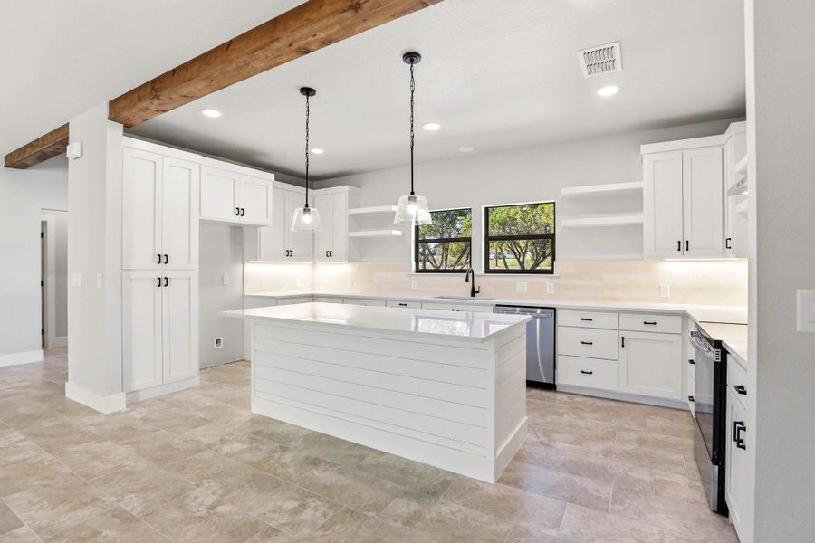 A well-appointed kitchen features a central island, tile flooring, and rustic wooden beams overhead. A well-appointed kitchen features a central island, tile flooring, and rustic wooden beams overhead.