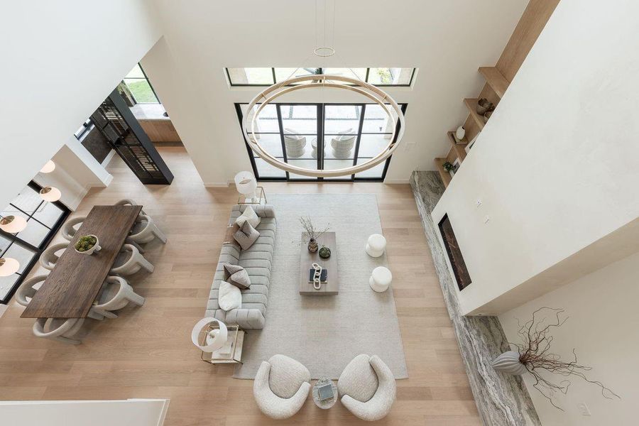 An elevated perspective showcases the grandeur of the great room, where expansive windows frame treetop views and natural light cascades through the open volume. The sculptural pendant becomes a focal point in motion, floating gracefully between levels.