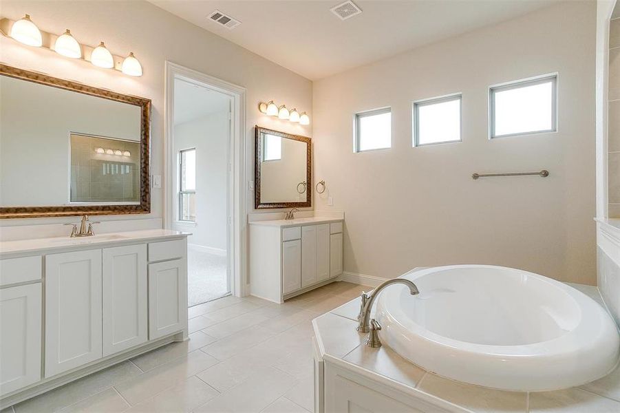 Bathroom with tile patterned flooring, a washtub, and double sink vanity