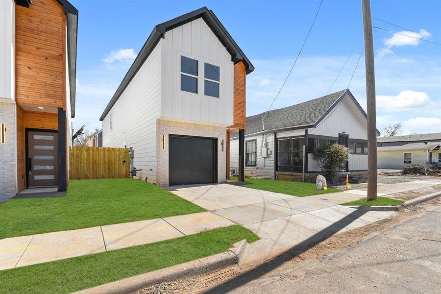 View of front of home with driveway, an attached garage, a front lawn, board and batten siding, and brick siding