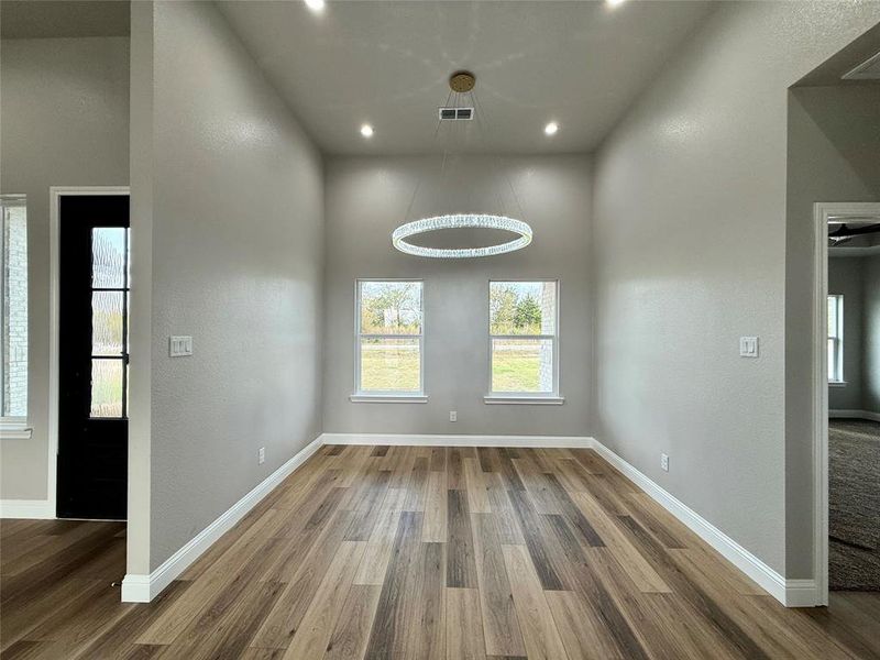 Unfurnished dining area featuring healthy amount of natural light, a textured wall, wood finished floors, and recessed lighting