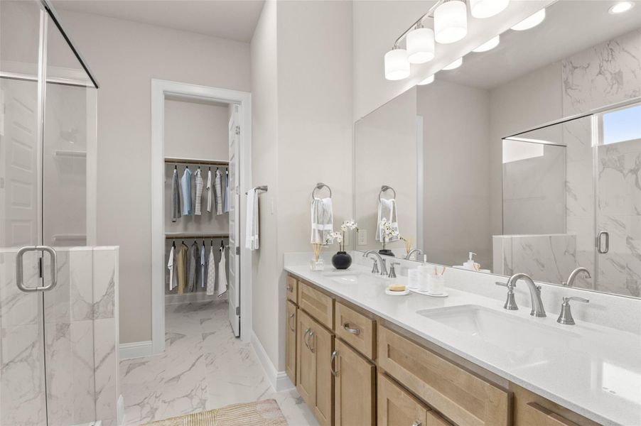 Full bath with marble finish floors, a marble finish shower, double vanity, baseboards, and a spacious closet