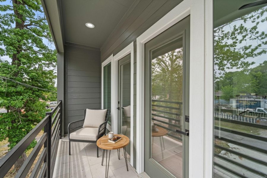 This covered upper-level balcony features dark gray horizontal siding, a light-colored tiled floor, and a black horizontal railing.
