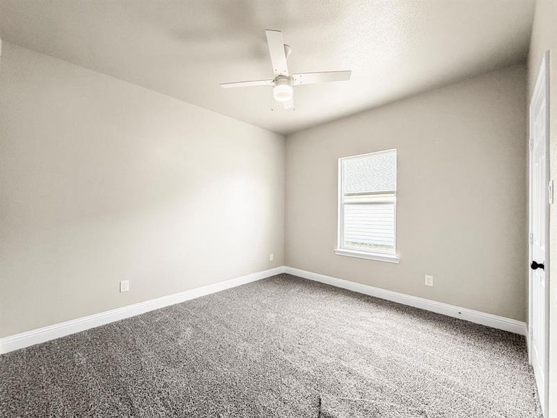 Carpeted spare room featuring baseboards and ceiling fan