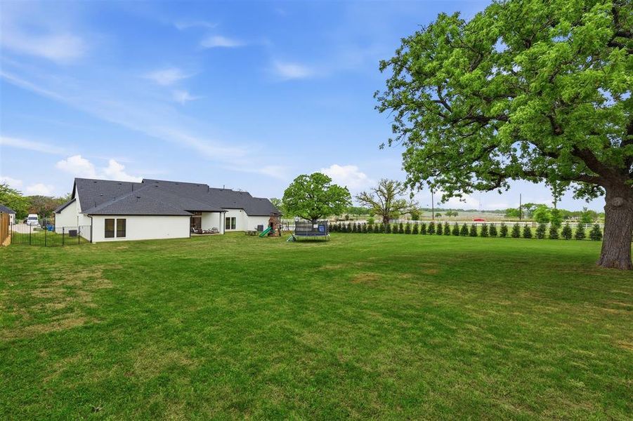 Fenced backyard with a trampoline and a patio area