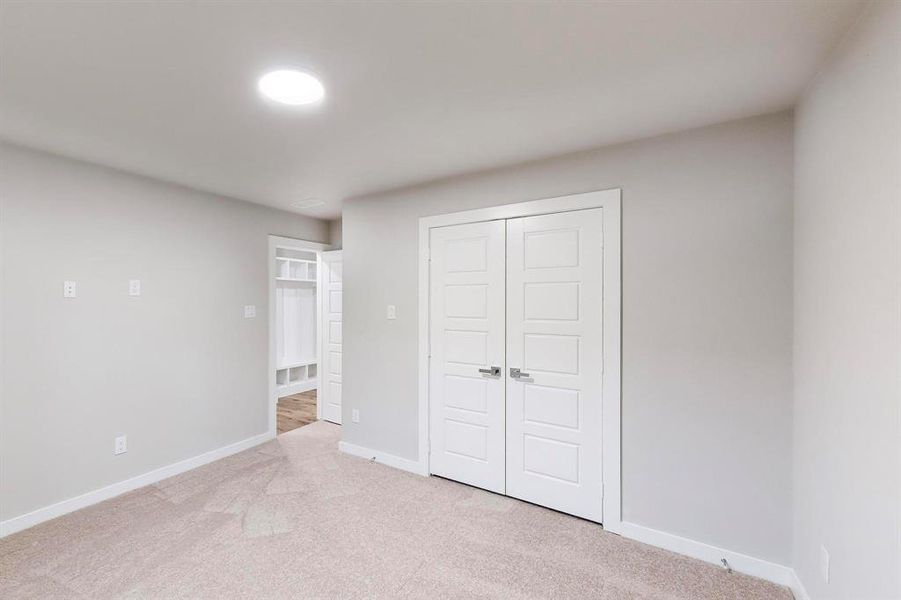 Unfurnished bedroom with light carpet and a closet