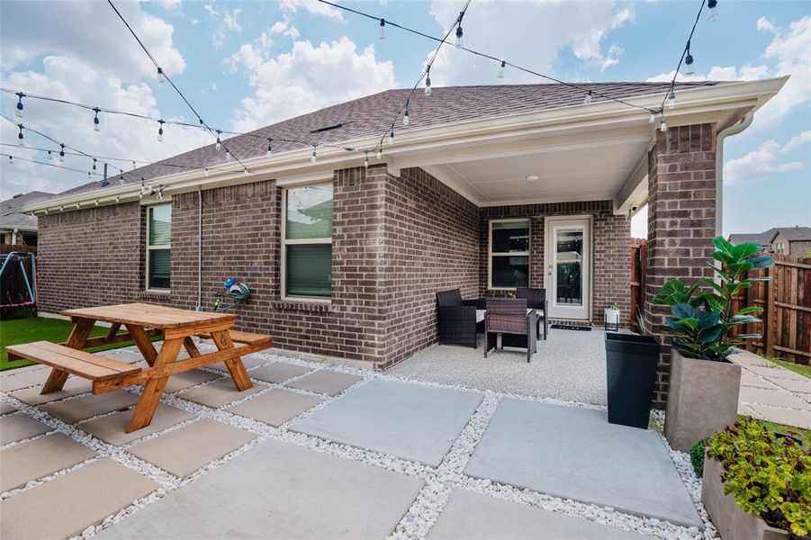 Back of house with brick siding, a shingled roof, and a patio area Back of house with brick siding, a shingled roof, and a patio area