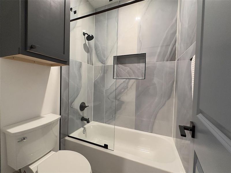 Bathroom with combined bath / shower with glass door and toilet