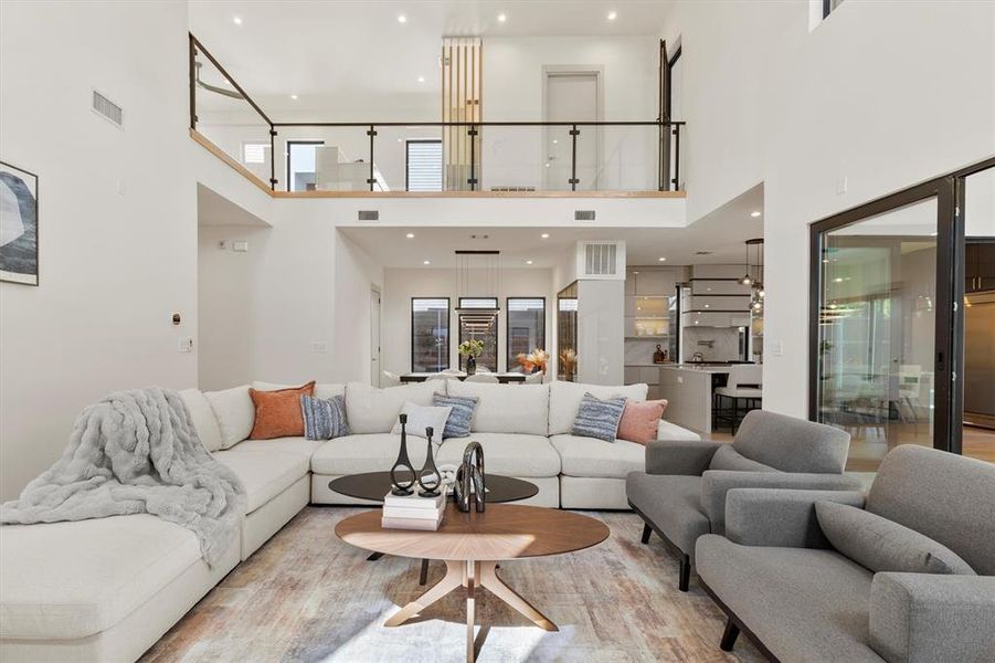 Living room with a towering ceiling and light hardwood / wood-style flooring