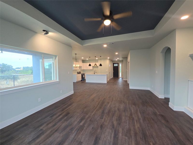 Unfurnished living room featuring recessed lighting, dark wood-style flooring, a raised ceiling, and a ceiling fan