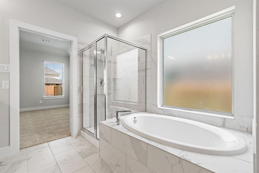 The primary en-suite has a soaking tub to give you that spa experience. The large privacy window allow lots of nature light in the space. Sample photo of completed home with similar floor plan. As-built interior colors and selections may vary.