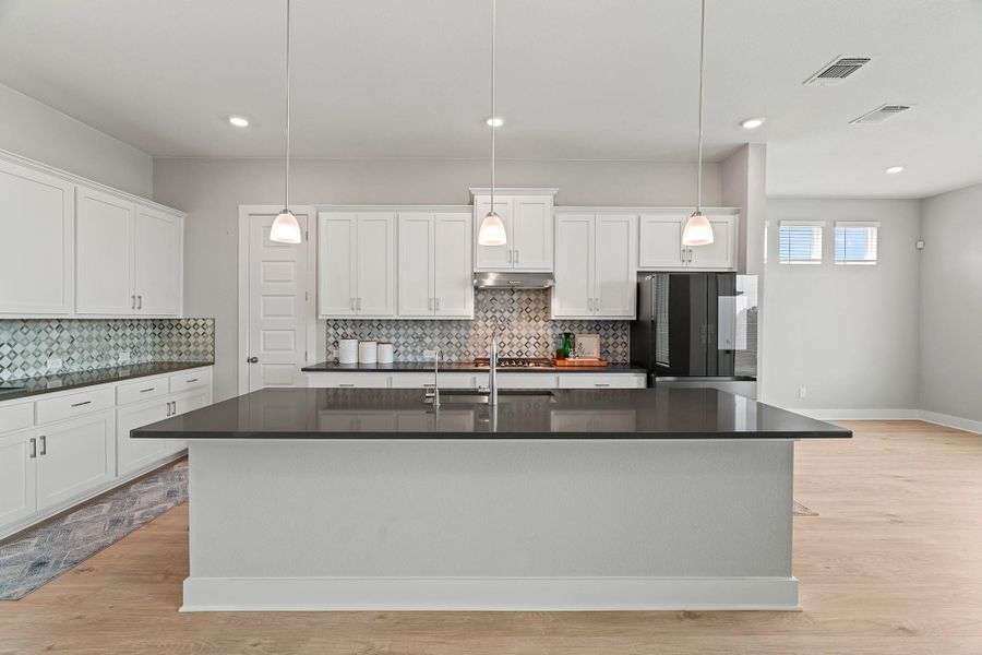 Kitchen with light wood-style flooring, decorative backsplash, a kitchen island with sink, and recessed lighting Kitchen with light wood-style flooring, decorative backsplash, a kitchen island with sink, and recessed lighting