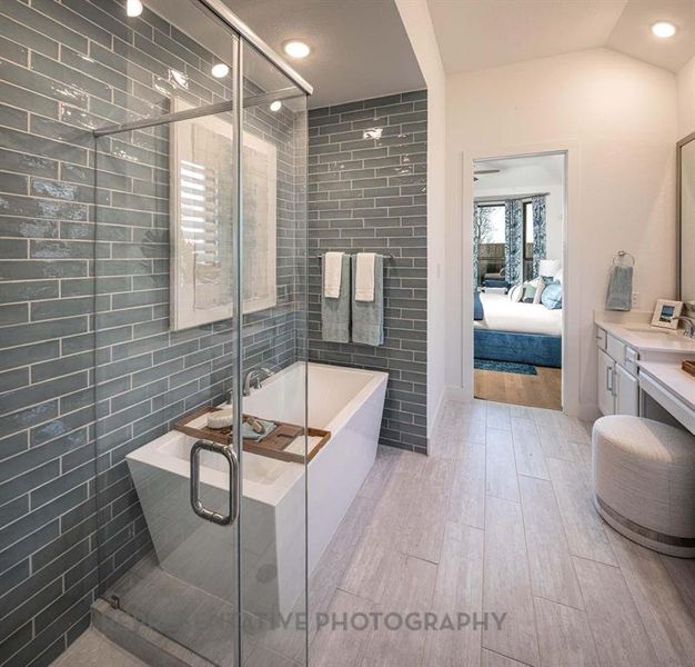 Ensuite bathroom featuring vanity, a freestanding bath, a stall shower, tile walls, and light wood-style floors Ensuite bathroom featuring vanity, a freestanding bath, a stall shower, tile walls, and light wood-style floors