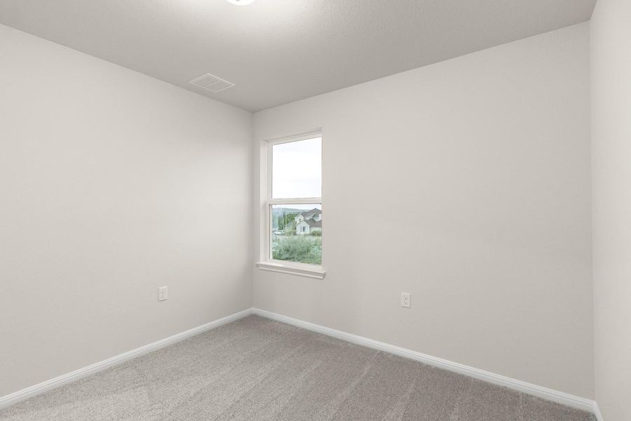 This room features light-colored walls, gray carpet, and a window providing natural light