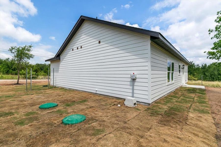 White horizontal siding exterior with a black roofline and dark trim, featuring multiple windows and a side entry