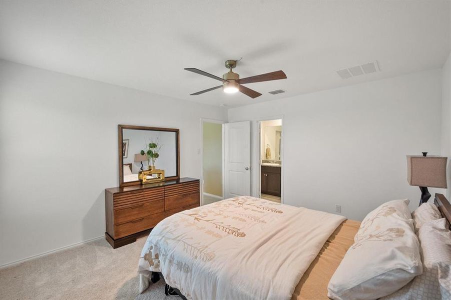 Bedroom featuring light colored carpet, a ceiling fan, and connected bathroom
