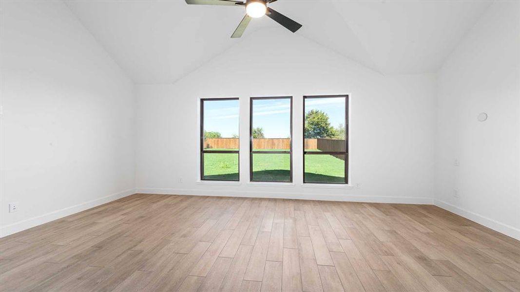 Empty room featuring light hardwood / wood-style flooring, high vaulted ceiling, and ceiling fan