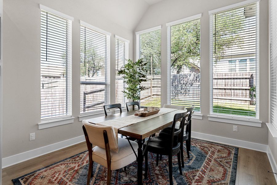 Dining area featuring a vaulted ceiling and a wall of tall windows with horizontal blinds