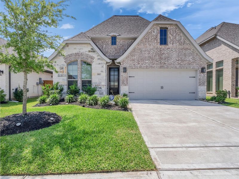 Charming brick home located in the gated section  with a spacious two-car garage, manicured lawn, and inviting front landscaping in a serene neighborhood.