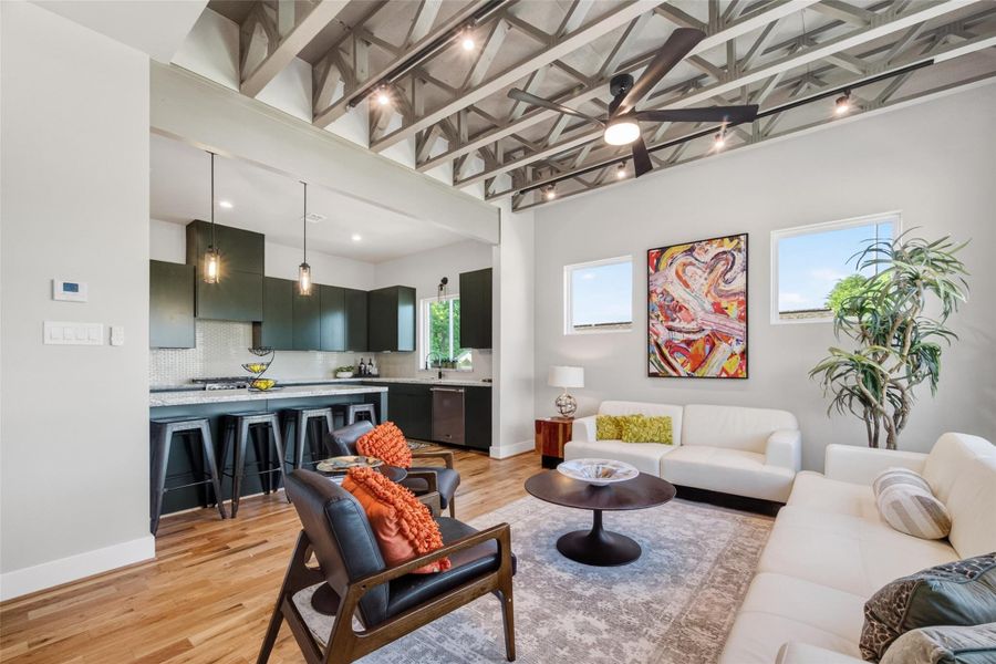 The open-plan second floor is the heart of the home. Soaring exposed trusses tie the living and kitchen areas together, while a 42" gas fireplace anchors the living room and the kitchen's dark flat-front cabinetry draws the eye. Wood floors and recessed lighting run throughout.