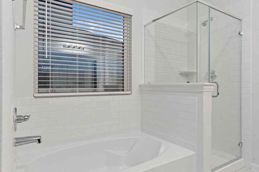 The spa-like design continues with a deep soaking tub positioned beside a large window for natural light and a separate glass-enclosed shower for a refreshing experience. A private haven to unwind after a long day.