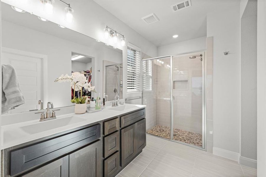 Full bath featuring a stall shower, double vanity, and light tile patterned floors Full bath featuring a stall shower, double vanity, and light tile patterned floors
