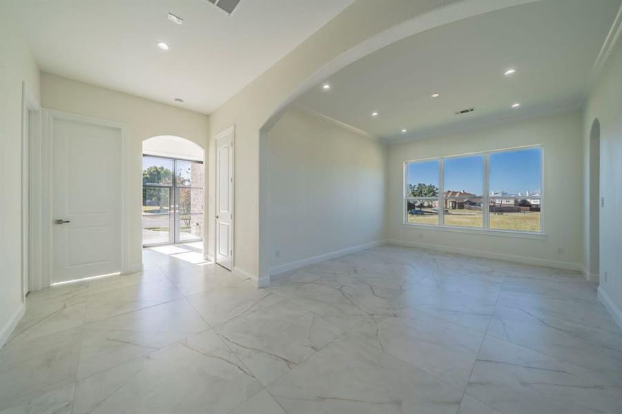 Empty room featuring arched walkways, light marble finish floors, recessed lighting, and ornamental molding Empty room featuring arched walkways, light marble finish floors, recessed lighting, and ornamental molding