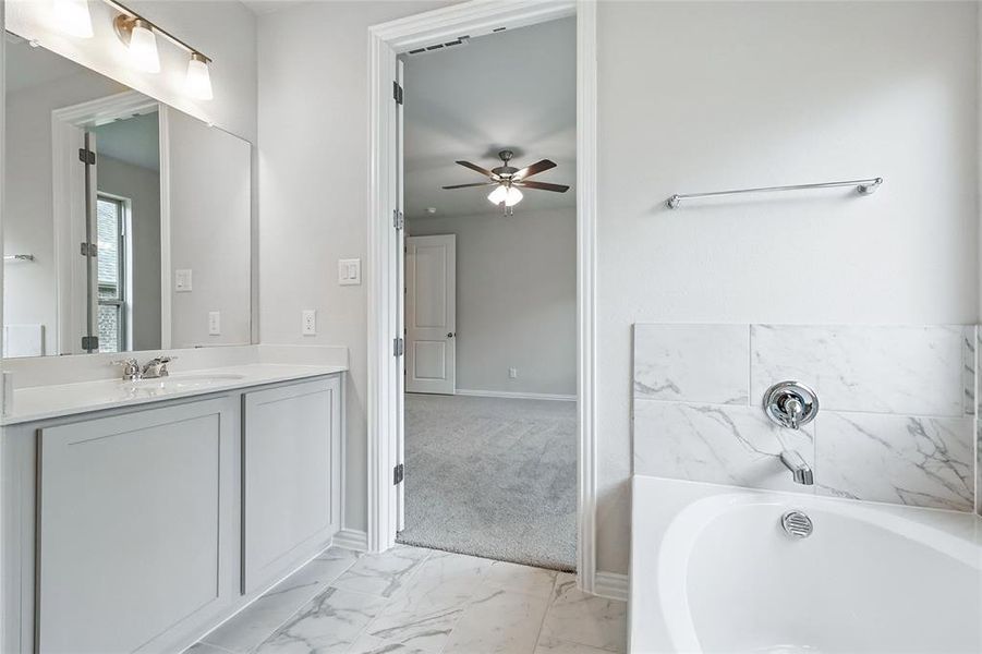 Bathroom with ceiling fan, a garden tub, vanity, and marble finish floors Bathroom with ceiling fan, a garden tub, vanity, and marble finish floors