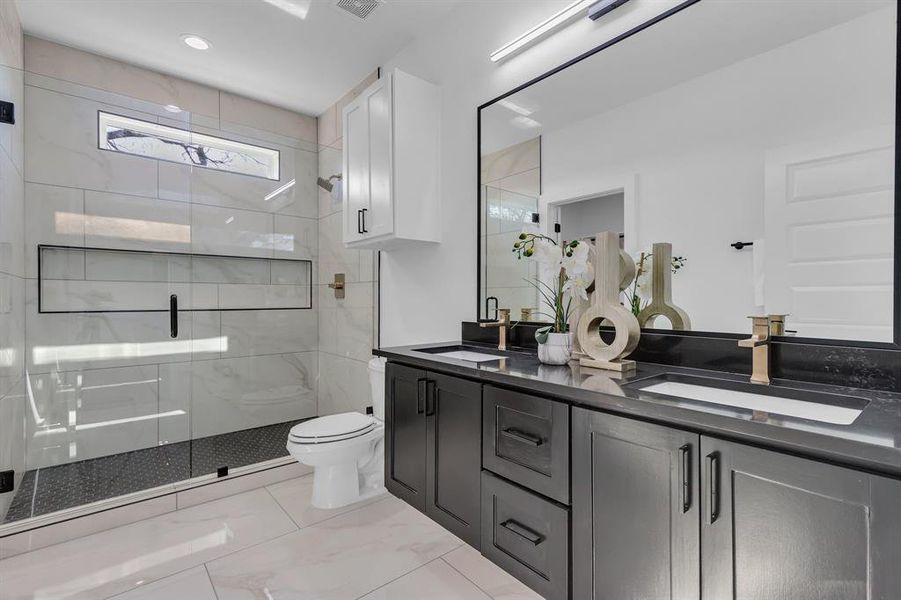 Bathroom featuring vanity, toilet, and a shower with door