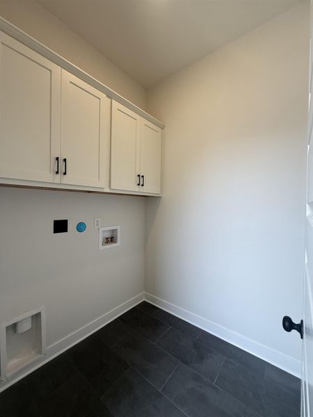 Laundry room featuring washer hookup, cabinet space, and dark tile patterned floors