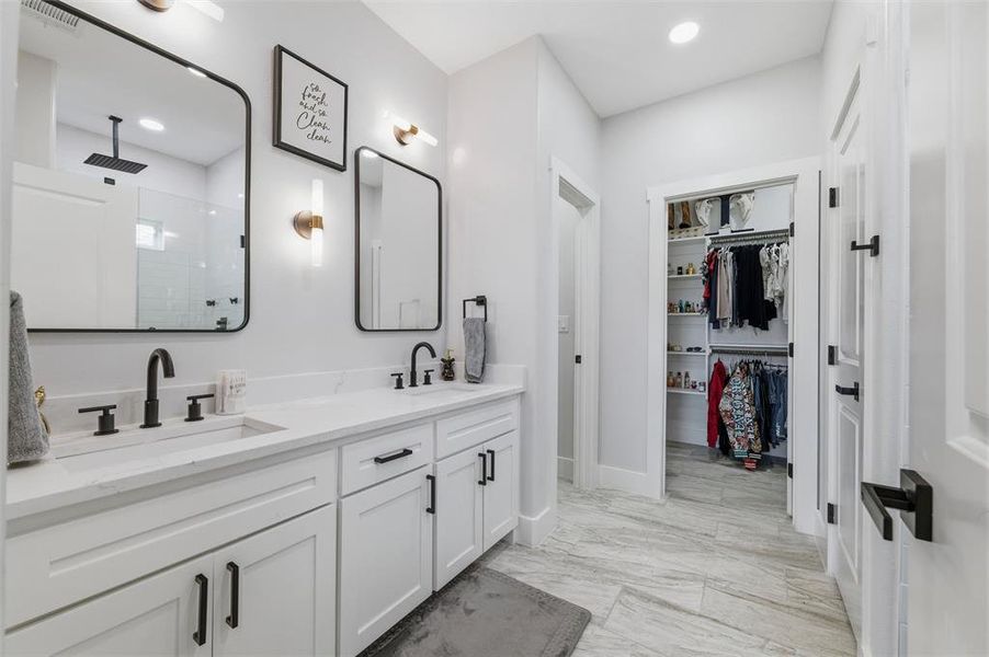 Full bathroom with double vanity, a stall shower, light marble finish flooring, a spacious Walk-in closet, and recessed lighting