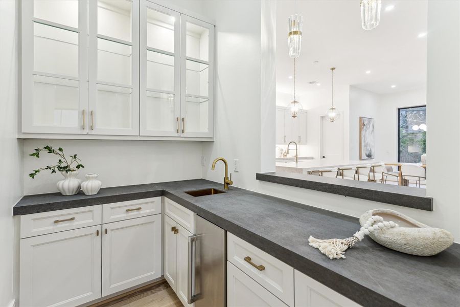 Wet bar features custom cabinetry, an ice maker, and a sink, conveniently located near the dining and living areas, making entertaining effortless.
