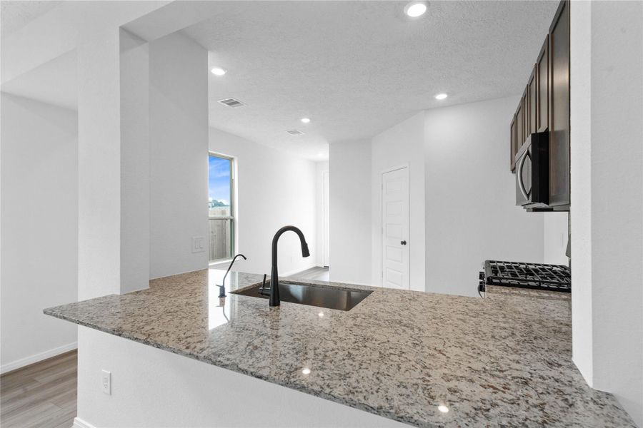 Highlighted here are the stunning White Napoli granite countertops. A built-in breakfast bar offers additional seating while seamlessly connecting the space to the kitchen.