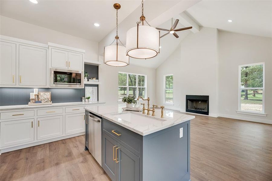 Kitchen featuring white cabinets, decorative light fixtures, beamed ceiling, high vaulted ceiling, and light wood-type flooring