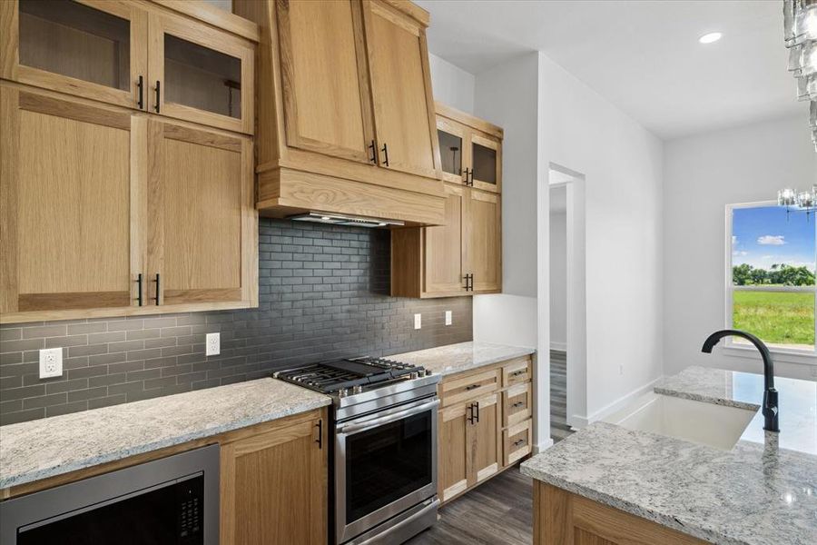 Kitchen with stainless steel appliances, tasteful backsplash, dark wood-type flooring, light stone countertops, and recessed lighting