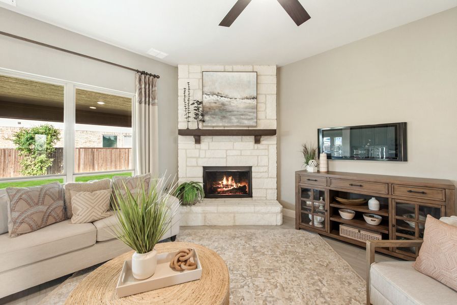 Living room with white brick corner fireplace, ceiling fan, sofa, and wood media console with wall-mounted TV