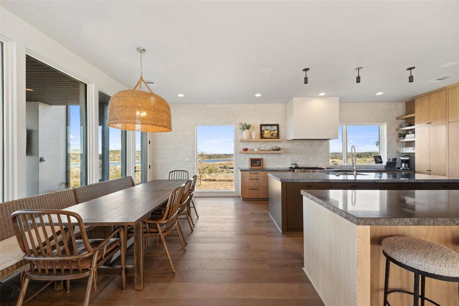 Kitchen with open shelves, a breakfast bar, dark wood-type flooring, dark stone counters, and recessed lighting