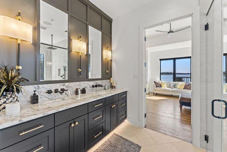 Full bath featuring a stall shower, double vanity, light tile patterned floors.