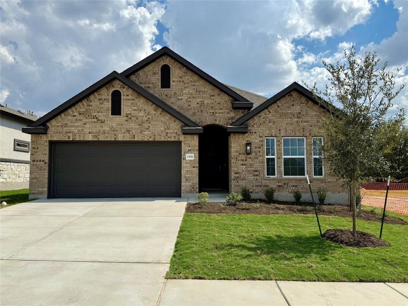 View of front facade with brick siding, a front yard, a garage, and driveway View of front facade with brick siding, a front yard, a garage, and driveway