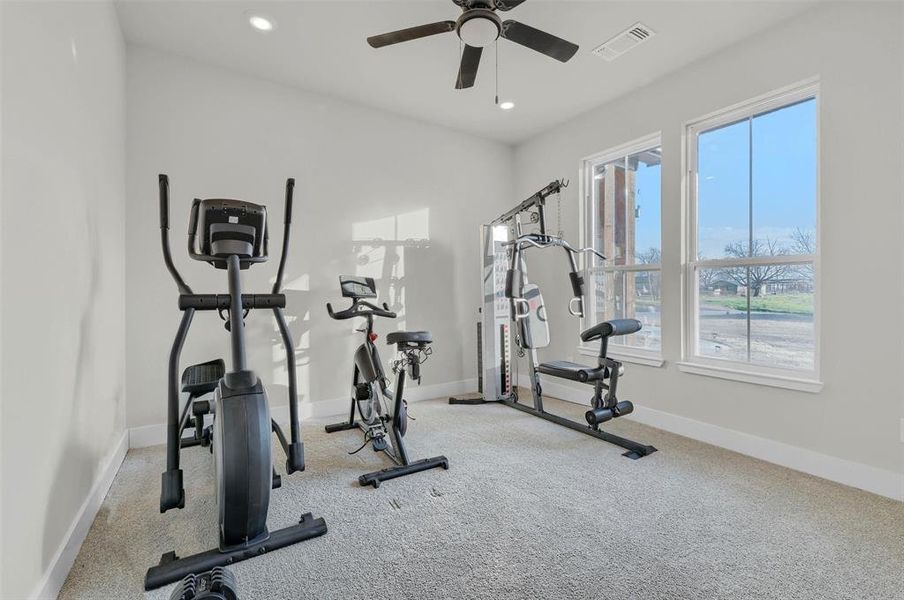 Workout area with light colored carpet and ceiling fan