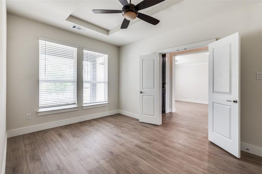 Spare room featuring ceiling fan, baseboards, light wood-style floors, and a tray ceiling Spare room featuring ceiling fan, baseboards, light wood-style floors, and a tray ceiling