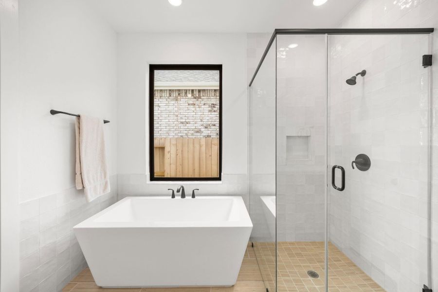 This large soaking tub and walk in glass shower is complimented with large white tiles surrounding the entire area.