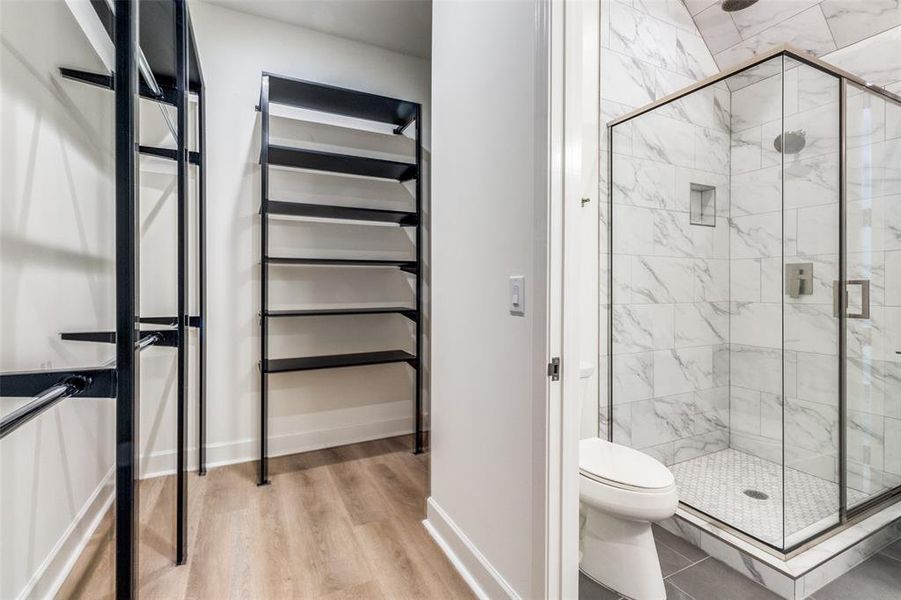 Bathroom featuring walk in shower, toilet, and hardwood / wood-style flooring