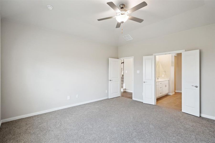 Unfurnished bedroom with high vaulted ceiling, light carpet, ceiling fan, and connected bathroom