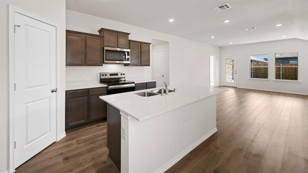 Kitchen with stainless steel appliances, dark wood finish cabinetry, a kitchen island with sink, recessed lighting, and dark wood-style floors