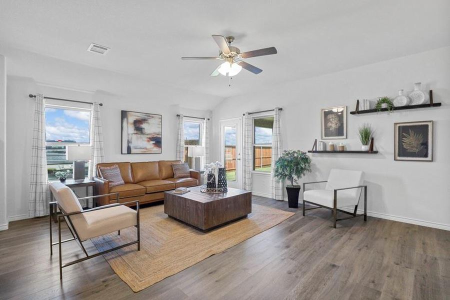 Living area with wood finished floors, plenty of natural light, a ceiling fan, and lofted ceiling