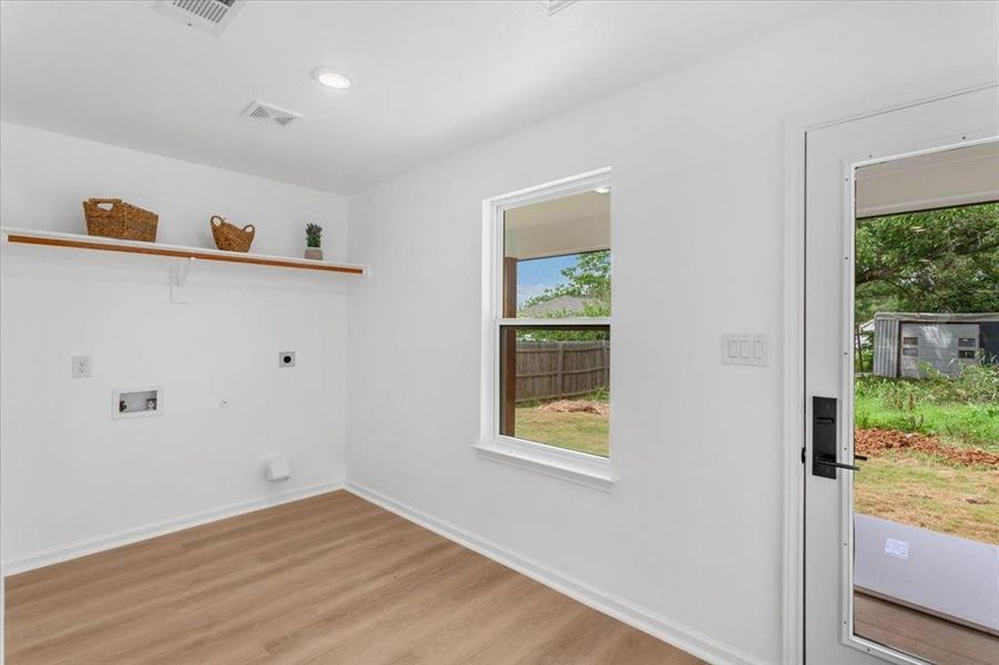 Washroom with light wood flooring, hookup for a washing machine, electric dryer hookup, and hookup for a gas dryer