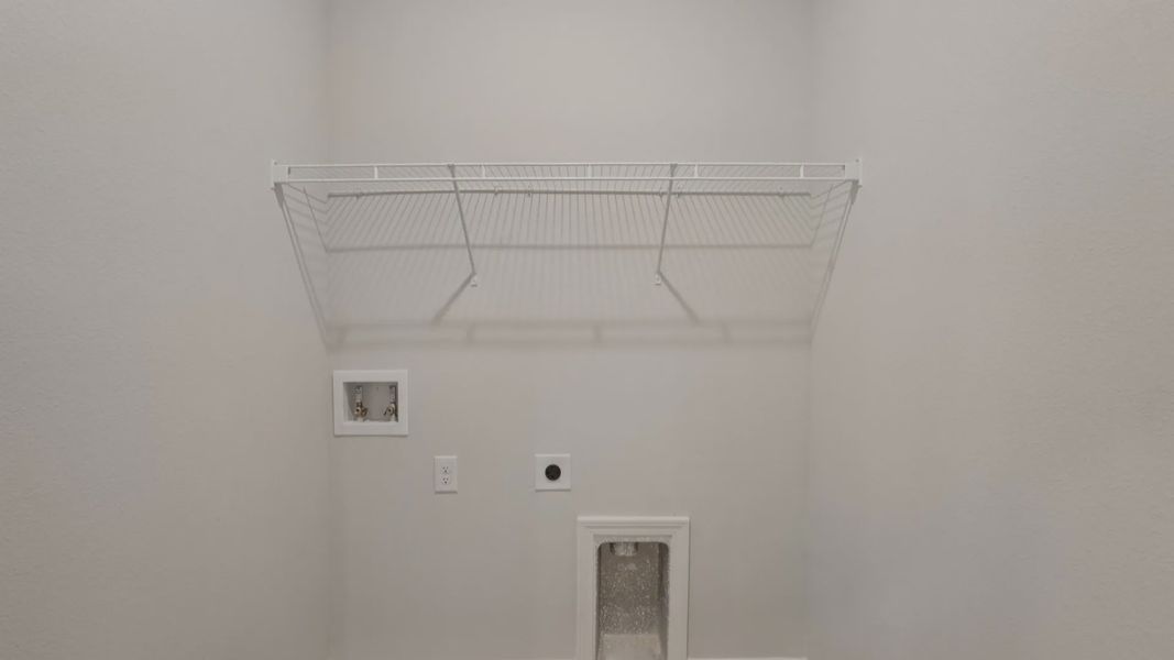 Elegant laundry room featuring wire shelving and rich wood flooring in Palm Coast’s Landmark - Deering plan.