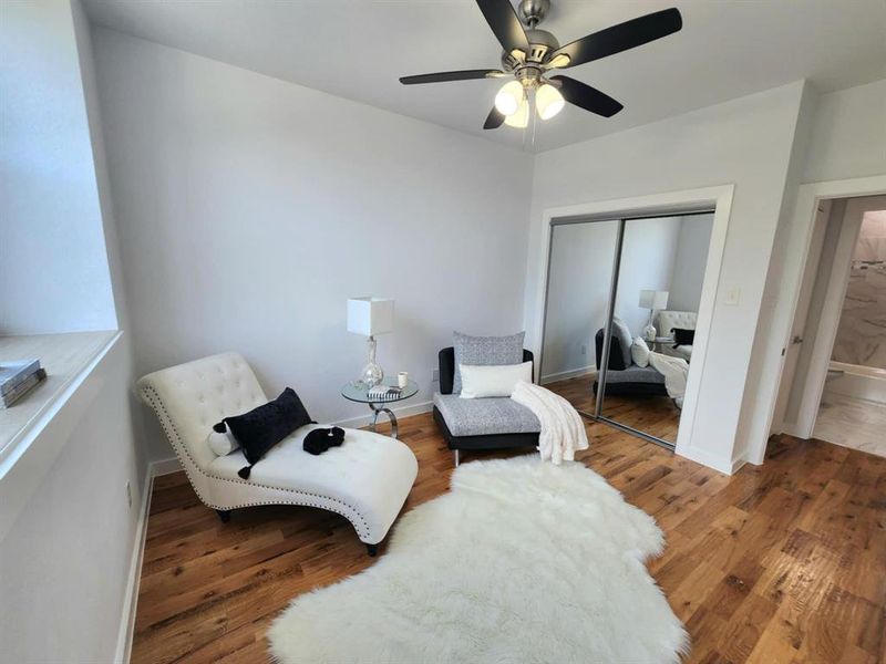 Living area with hardwood / wood-style floors and ceiling fan