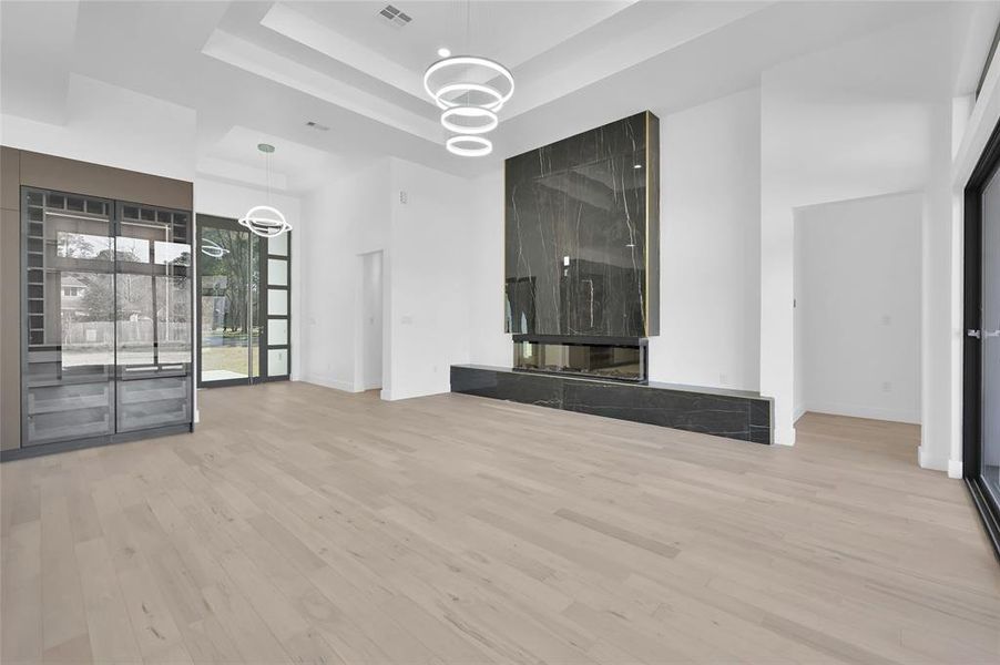 This modern living space features sleek hardwood floors, a striking black marble fireplace, and an abundance of windows for natural light.